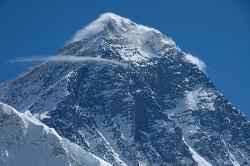 Mount Everest; a massive black pyramid; fog lies like a veil on its summit.