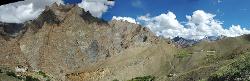 Panorama with some tents at the very left; and a little pass in the dip of the ridge at the right.