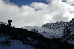 Porter arriving at the flat valley before the pass. Kishong La lies in the middle of the picture, just left of the where the rocky ridge drops and joins the level snow line.